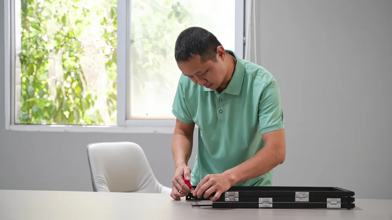 Technician checking black metal furniture components at a workbench